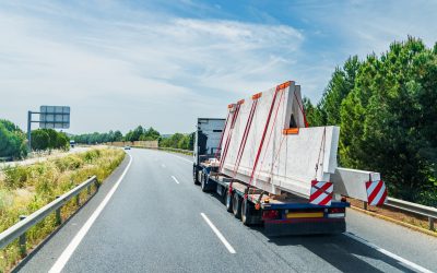 Truck transporting large concrete panels on a highway, showcasing the challenges and opportunities for truck drivers in spring.